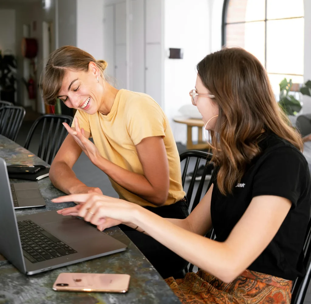 Two women having a conversation with laptop nearby